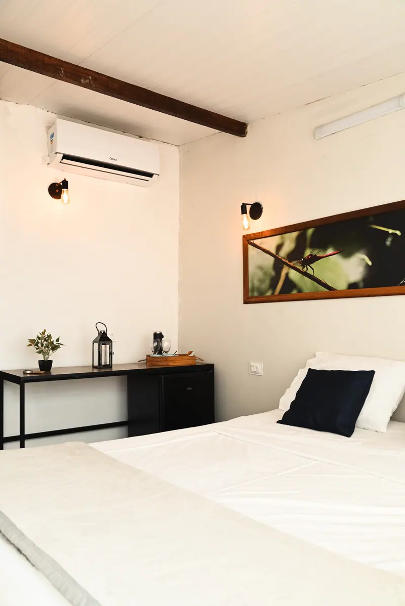 Quarto com cama de roupa branca, ar-condicionado, escrivaninha e quadro