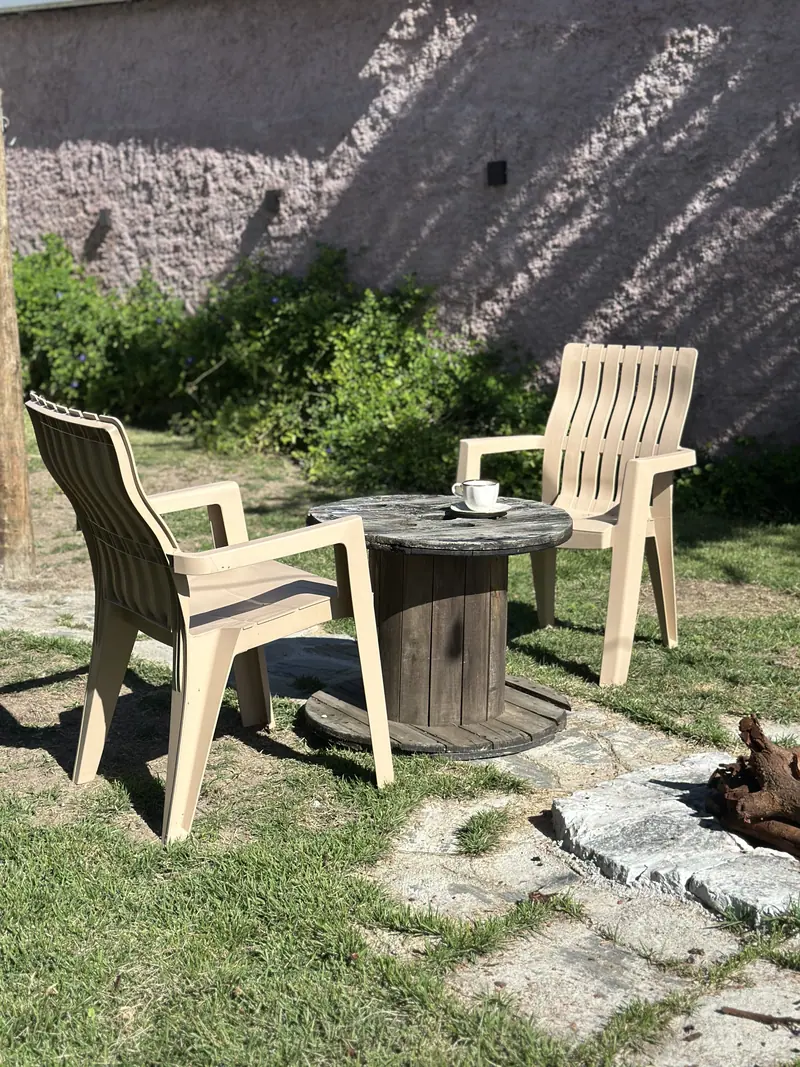 Cantinho externo no jardim com duas cadeiras e mesa de carretel